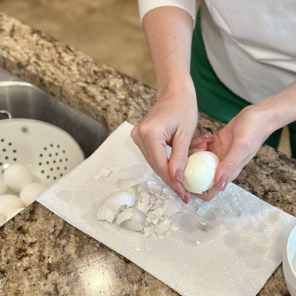 Close-up of hands peeling a perfectly cooked hard-boiled egg, demonstrating the easy-peel method.