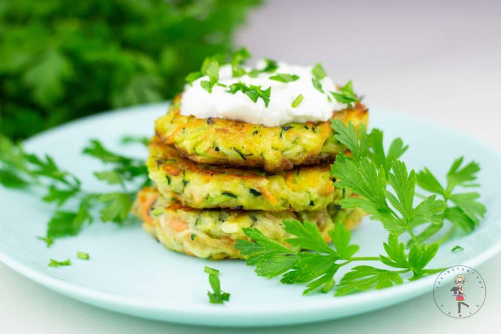 Crispy zucchini fritters served on a white plate, garnished with fresh herbs, showcasing a delicious vegetarian appetizer.