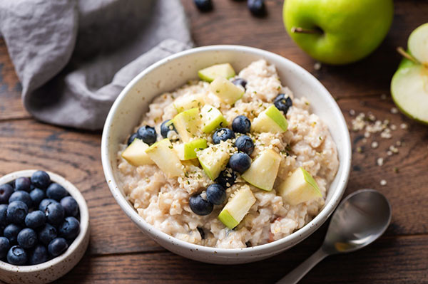 Bowl of oatmeal with blueberries and apple, illustrating a healthy breakfast choice for acid reflux management. This fiber-rich meal is gentle on the stomach and helps prevent heartburn.