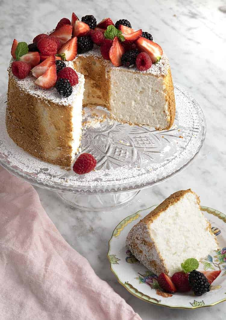 Angel food cake with berries on a crystal cake plate.