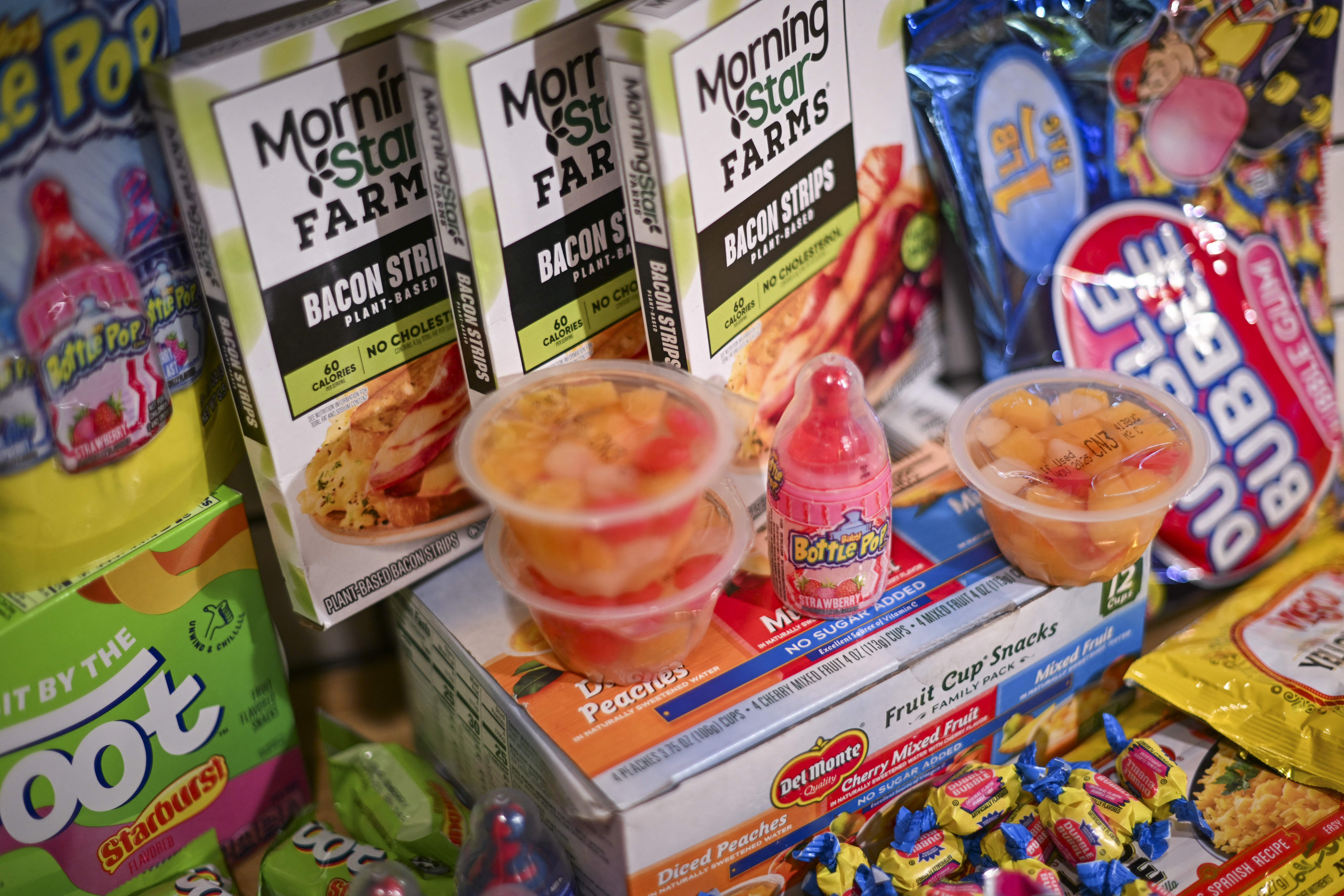 Various food products including Bazooka Ring Pop Lollipops, Starburst Fruit By The Foot snacks, Double Bubble Bubble gum, Baby Bottle Pop candy, all known to use Red Dye #3, displayed in an illustration photograph.