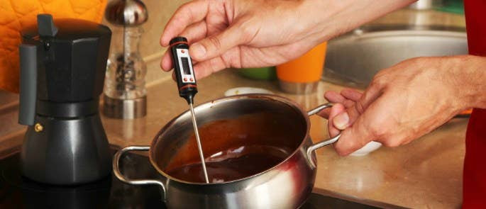 Image depicting a probe thermometer inserted into a chocolate mixture, demonstrating accurate temperature measurement for food safety and quality control.