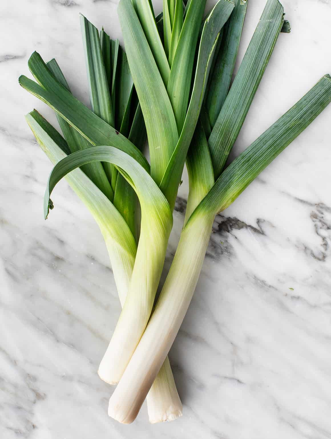 Fresh leeks displayed, highlighting their long, cylindrical shape and layers, showcasing a versatile vegetable for cooking.