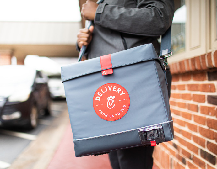 Chick-fil-A delivery driver handing a bag of food to a customer.