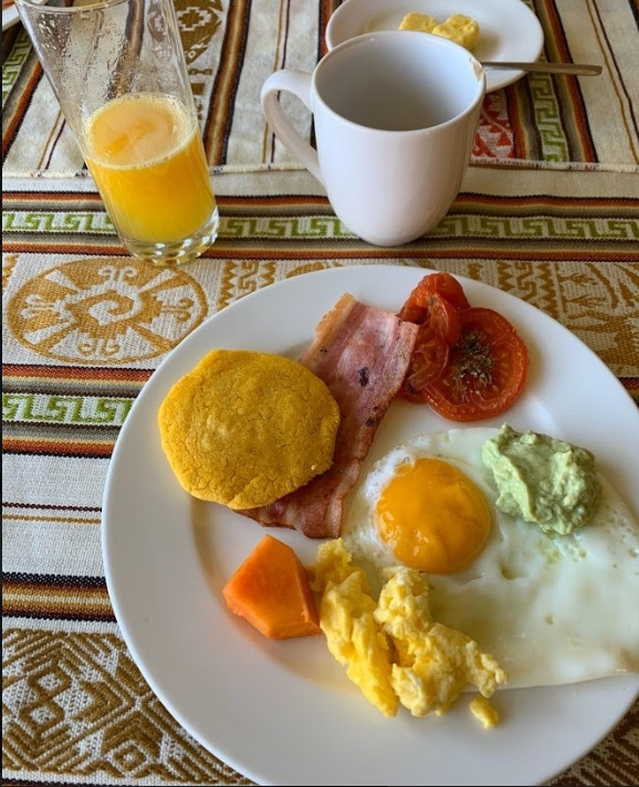 Traditional Ecuadorian breakfast with fried eggs, plantains, avocado, and fruit.