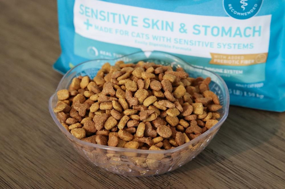 Purina ONE +Plus Sensitive Skin &amp; Stomach kibble in a white bowl, ready to be served to a cat