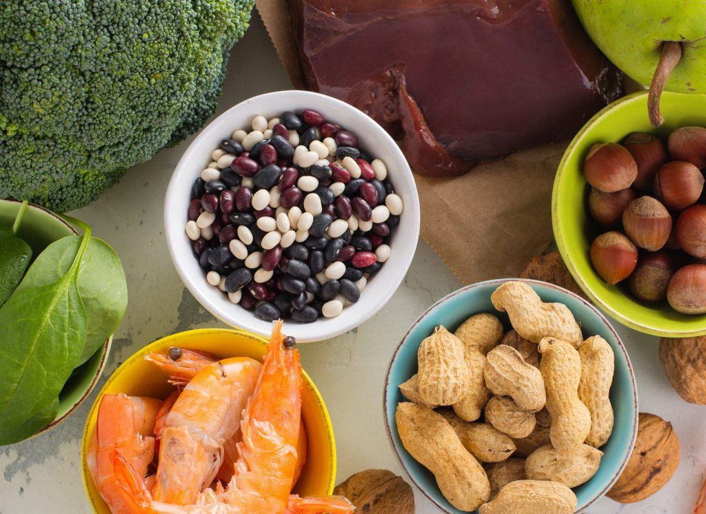 A colorful array of folate-rich foods including leafy green vegetables, legumes, fruits, and nuts, highlighting dietary sources of vitamin B9.