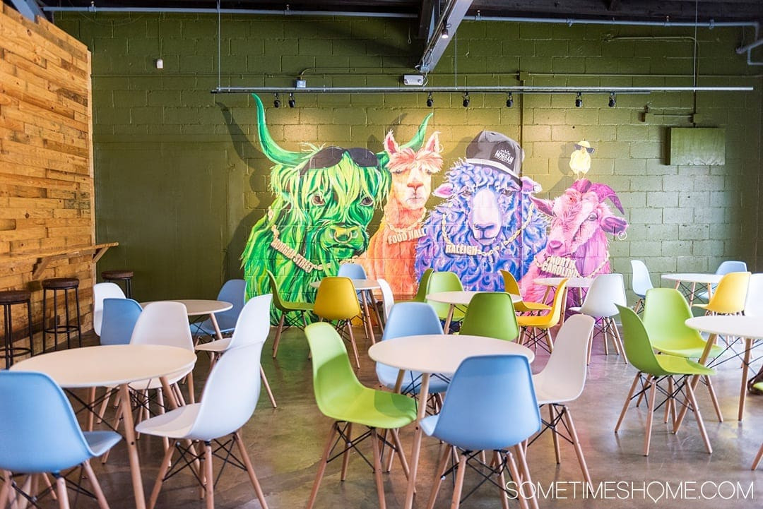 The interior of Morgan Street Food Hall in Raleigh, NC, showcasing its industrial design with exposed beams and modern seating.