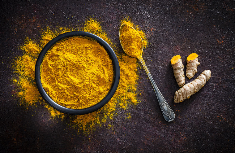 Overhead shot of vibrant turmeric roots and powder, showcasing the spice in both fresh and ground forms.