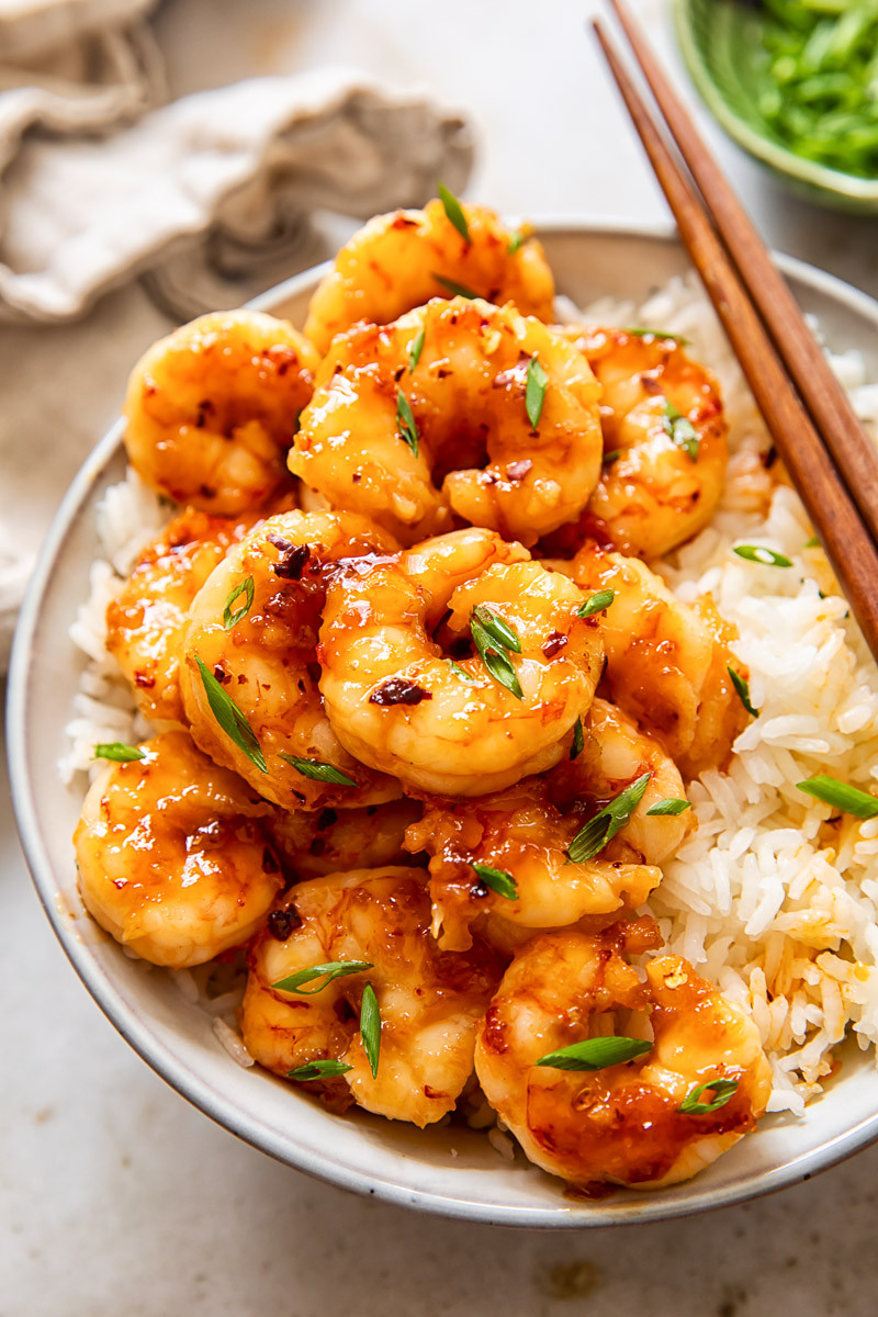 A bowl of rice topped with glazed shrimp.