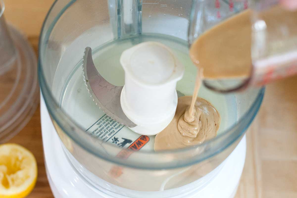 Tahini and lemon juice being processed in a food processor.