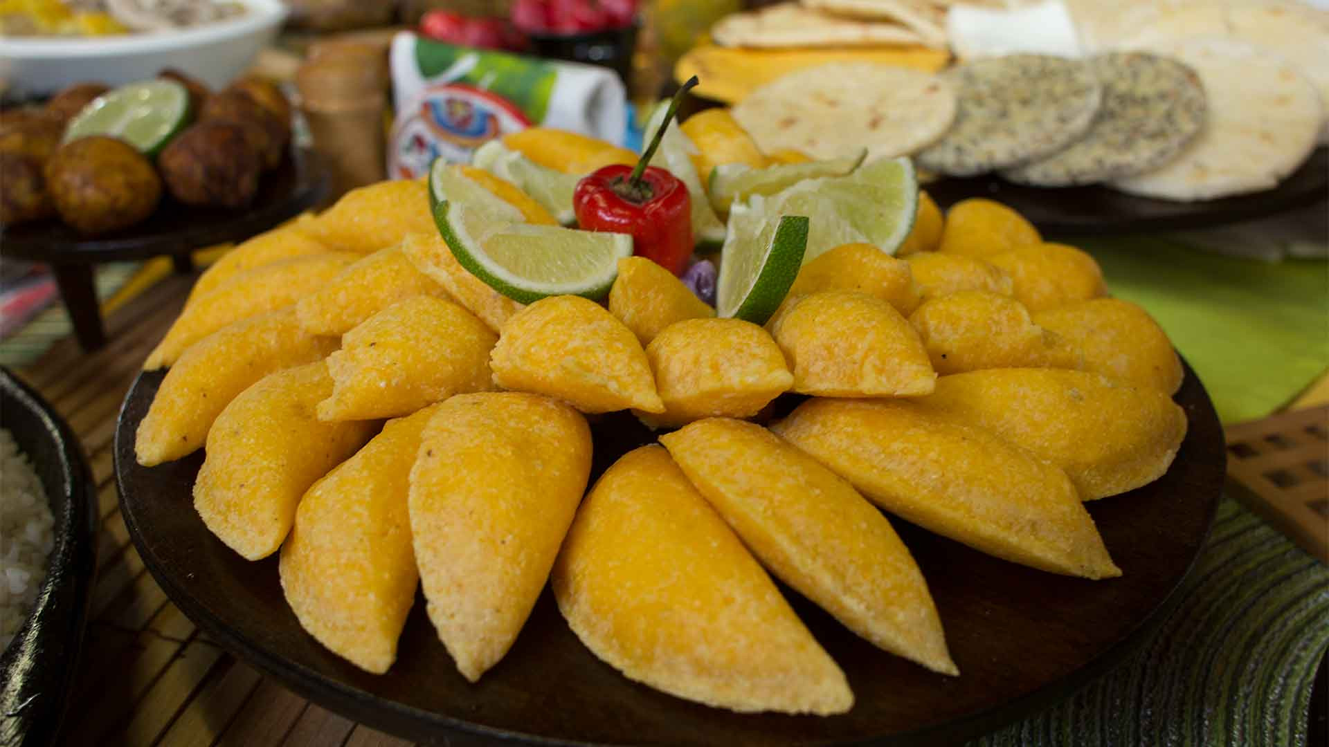Close-up of Colombian empanadas, showcasing their golden-brown, deep-fried exteriors and diverse fillings such as seasoned ground meat, potatoes, and vegetables, topped with a wedge of lime for added flavor.