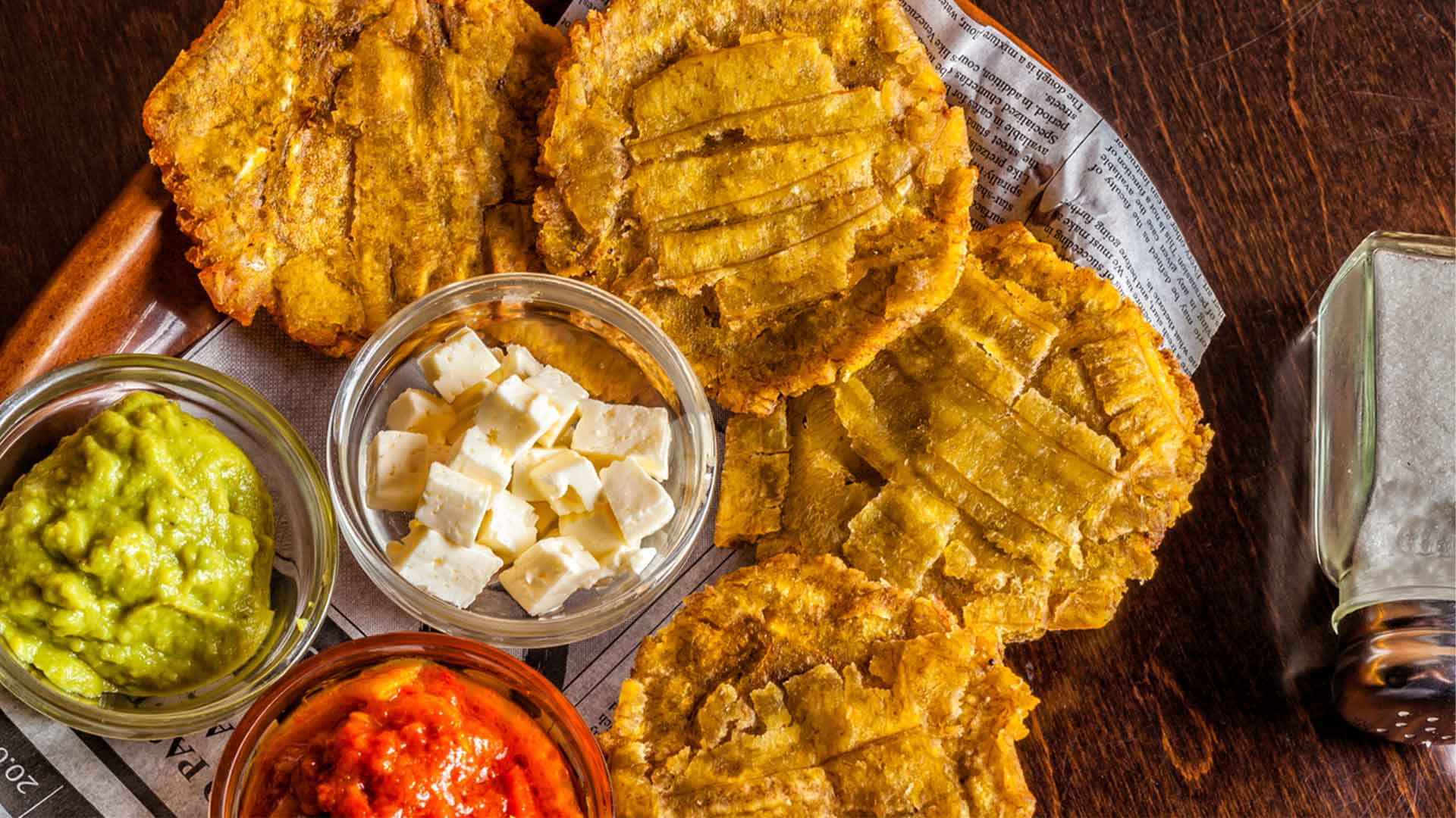 A plate of Colombian patacones, featuring flattened and twice-fried green plantains topped with beans, shredded meat, hogao (tomato-based relish), guacamole, and cheese, showcasing the creative and delicious use of bananas in Colombian cuisine.