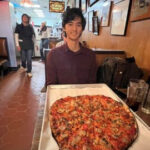 Sally's Apizza medium pie on a sheet tray at a booth table, New Haven