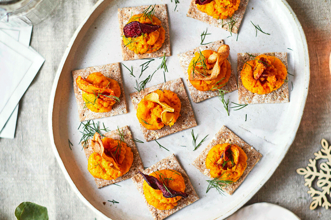 Carrot purée on oat crackers on a round serving plate