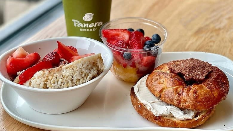 A bagel, fruit cup, oatmeal with strawberries, and drink from Panera