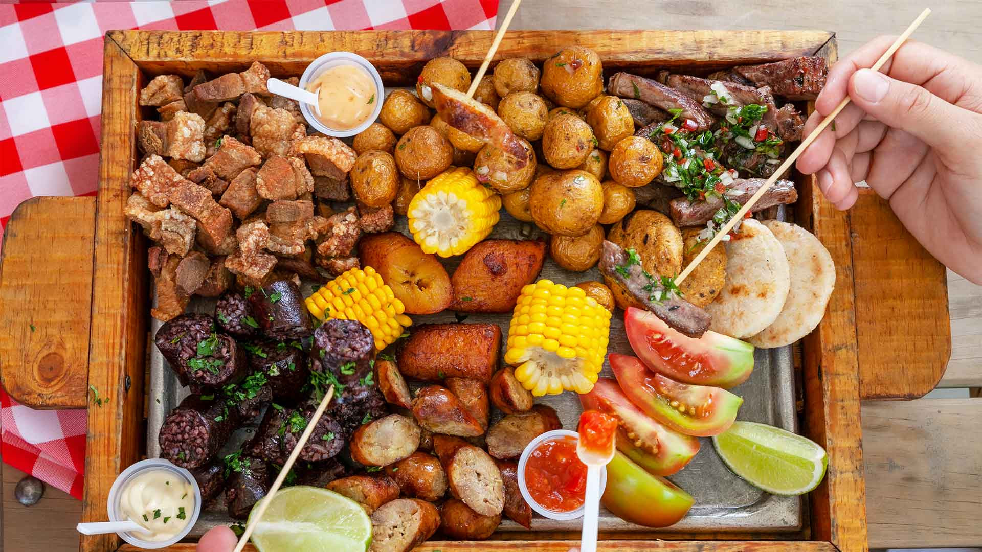 A generous platter of Colombian Fritanga, featuring an assortment of grilled and fried meats such as chicharrón (crispy pork rind), chorizo, morcilla (blood sausage), beef, and chicken, perfect for sharing and experiencing a variety of textures and flavors.