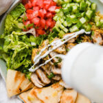 halal chicken and rice bowls with squeeze bottles of white sauce and red sauce