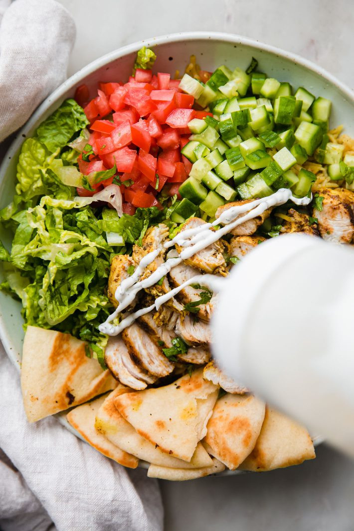 halal chicken and rice bowls with squeeze bottles of white sauce and red sauce