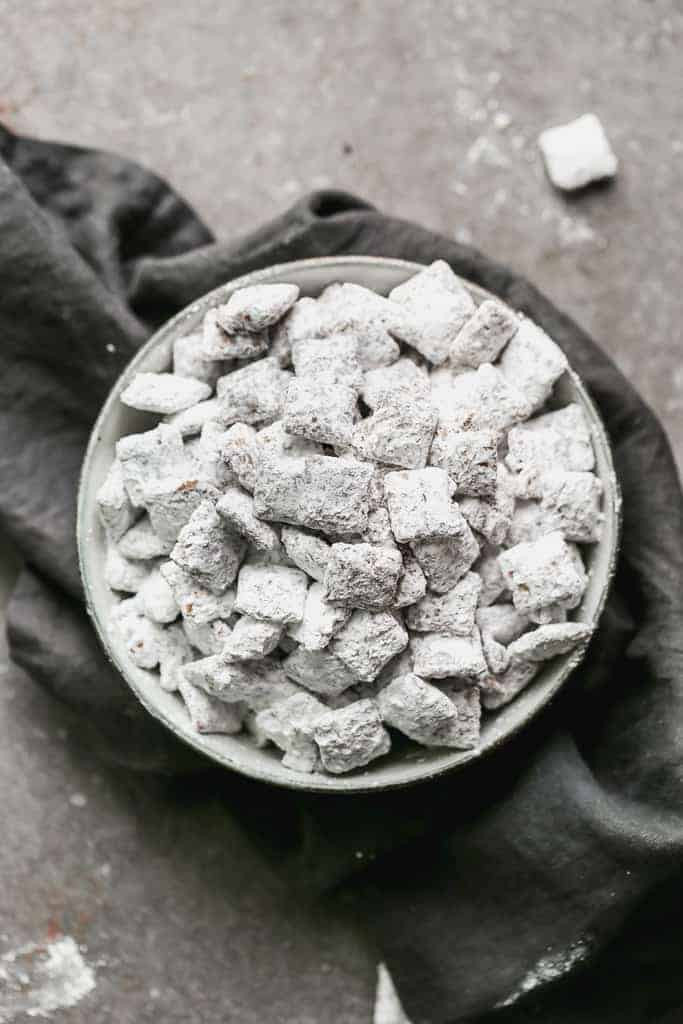 A bowl of Muddy Buddies, also known as Puppy Chow, on a grey hand towel, highlighting its appealing texture and appearance.