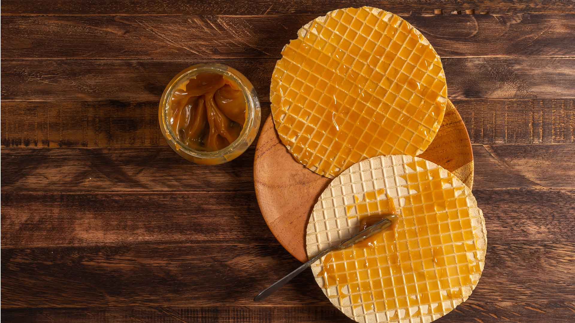 A Colombian Oblea, featuring thin brown wafers sandwiched together with arequipe (caramel), jam, chocolate, shredded coconut, and cheese, showcasing its customizable and delicious nature as a must-try street food dessert.