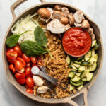ingredients for one pot pasta arranged in cooking pan before cooking on marble background