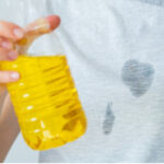 Woman carefully blotting a grease stain on her clothing with a clean cloth, showcasing immediate stain treatment