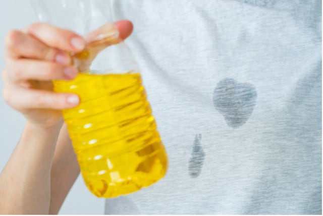Woman carefully blotting a grease stain on her clothing with a clean cloth, showcasing immediate stain treatment