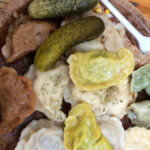 Close-up of assorted Polish pierogi with various fillings, topped with fried onions and sour cream