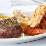 Steak, lobster, grilled lemon and butter sauce on a plate