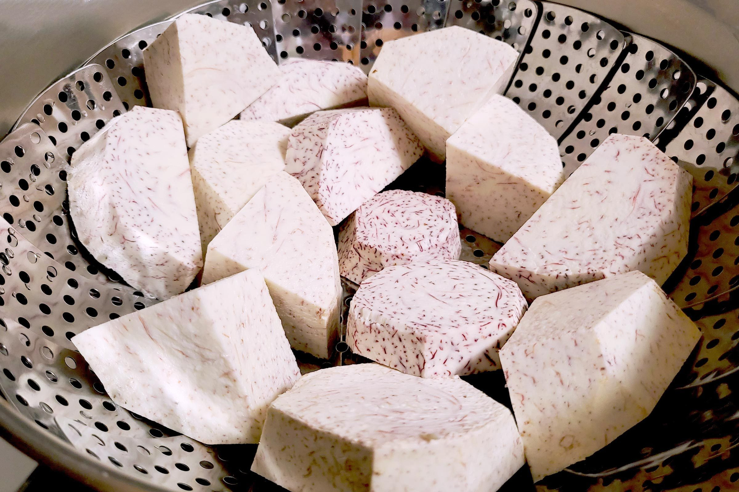 Steamed taro root chunks in a steamer basket